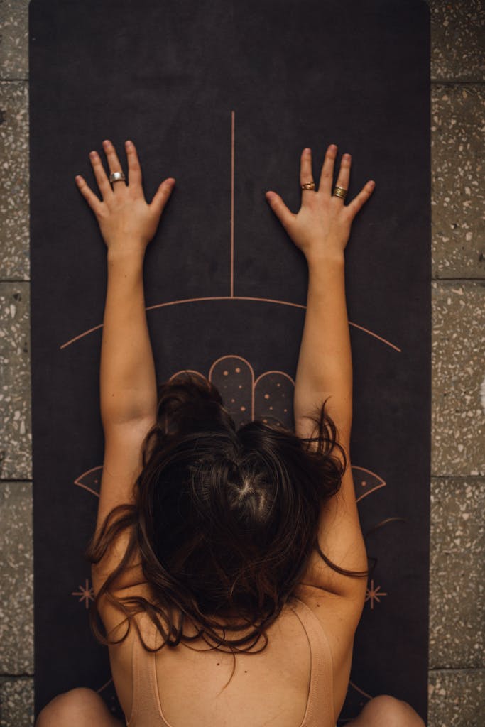 Woman practicing calming yoga pose on a detailed mat indoors.