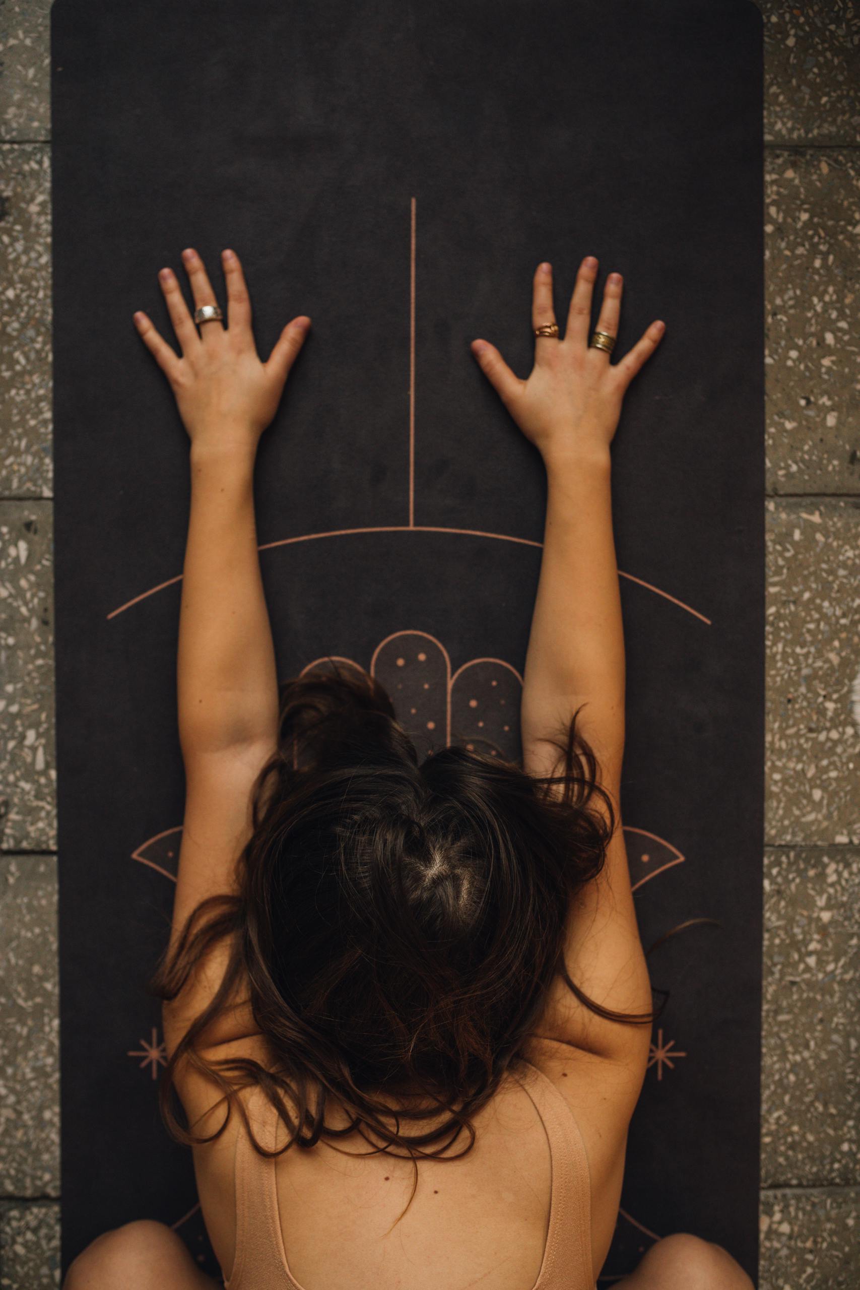 Woman practicing calming yoga pose on a detailed mat indoors.